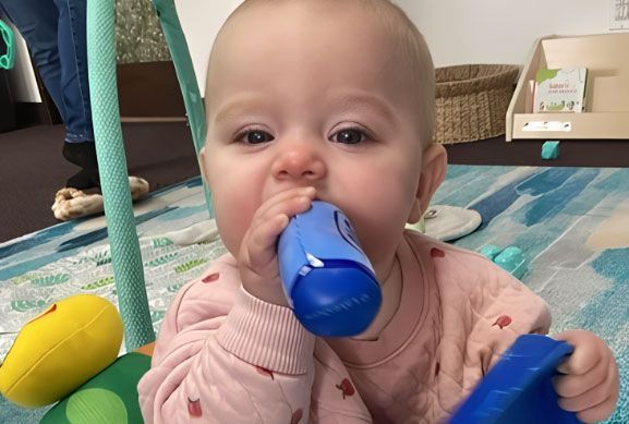 Montessori infant holding and exploring a blue container.