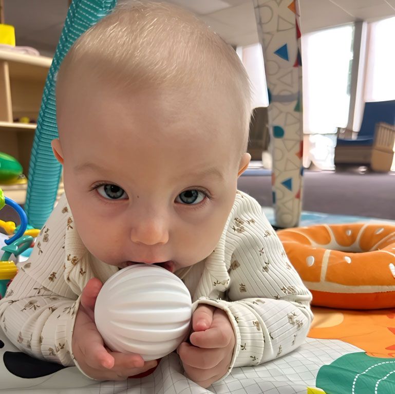 Montessori infant exploring a white sensory ball.