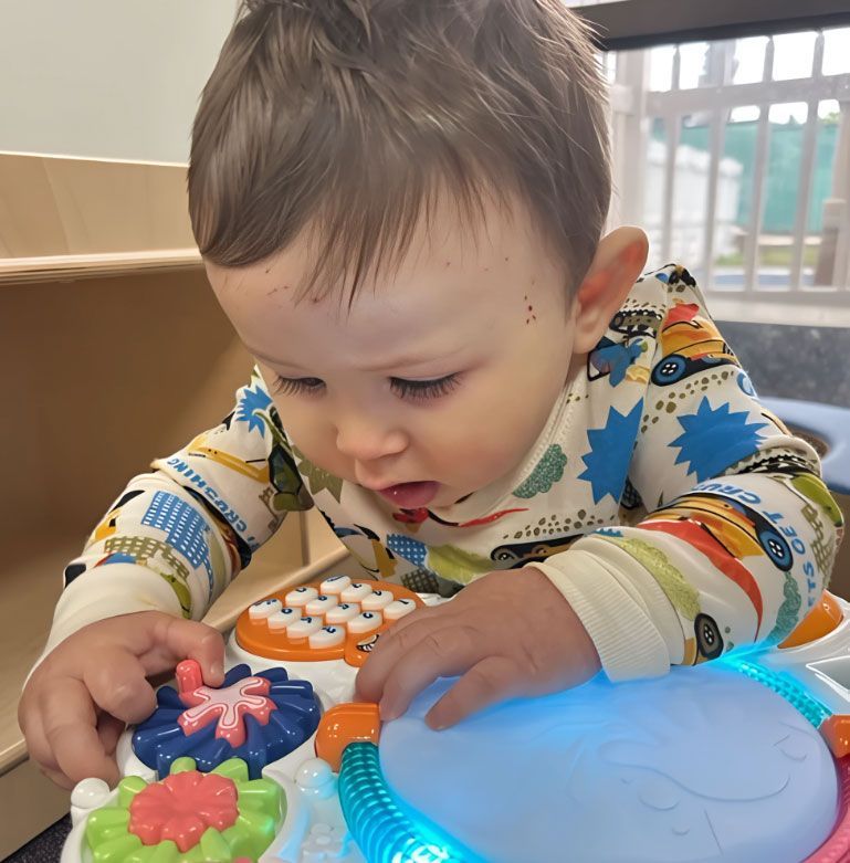 Montessori infant playing with a light-up activity center in classroom.