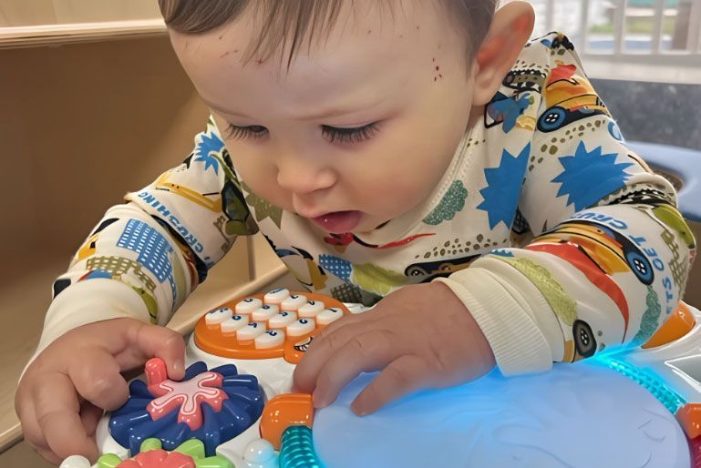 Montessori infant exploring a light-up activity toy.