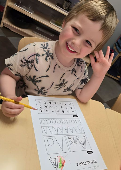 Happy child tracing the letter A with a pencil in a Montessori class.