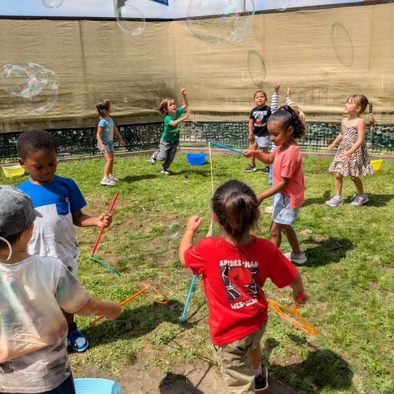 Montessori children playing outdoors with bubbles.