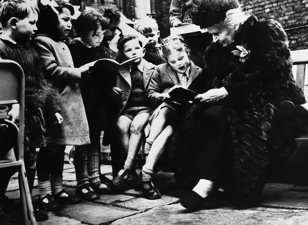 Dr. Maria is reading a book to a group of children.