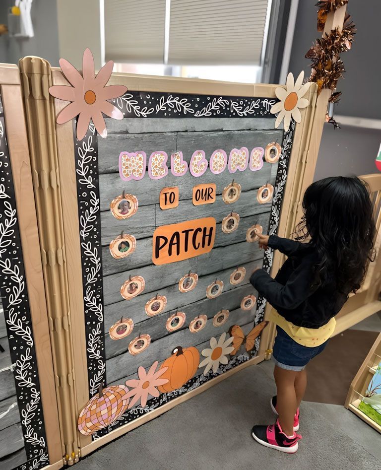 Montessori child interacts with a seasonal fall display.