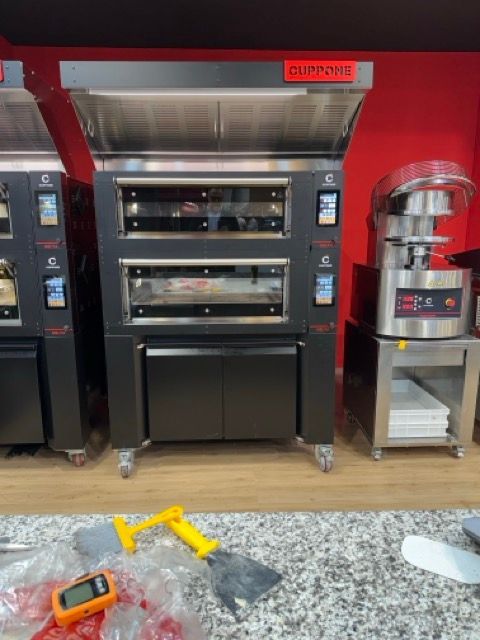 Cuppone Delta pizza oven in stainless steel for professional kitchens
Chef baking pizza in Cuppone Alpha oven with digital controls
Cuppone commercial pizza oven installed in modern pizzeria
Cuppone PizzaForm dough press machine preparing fresh pizza bases
Close-up of Cuppone HE400 pizza oven with energy-efficient design
Cuppone Italian pizza ovens showcased at Fine Food Sydney exhibition
