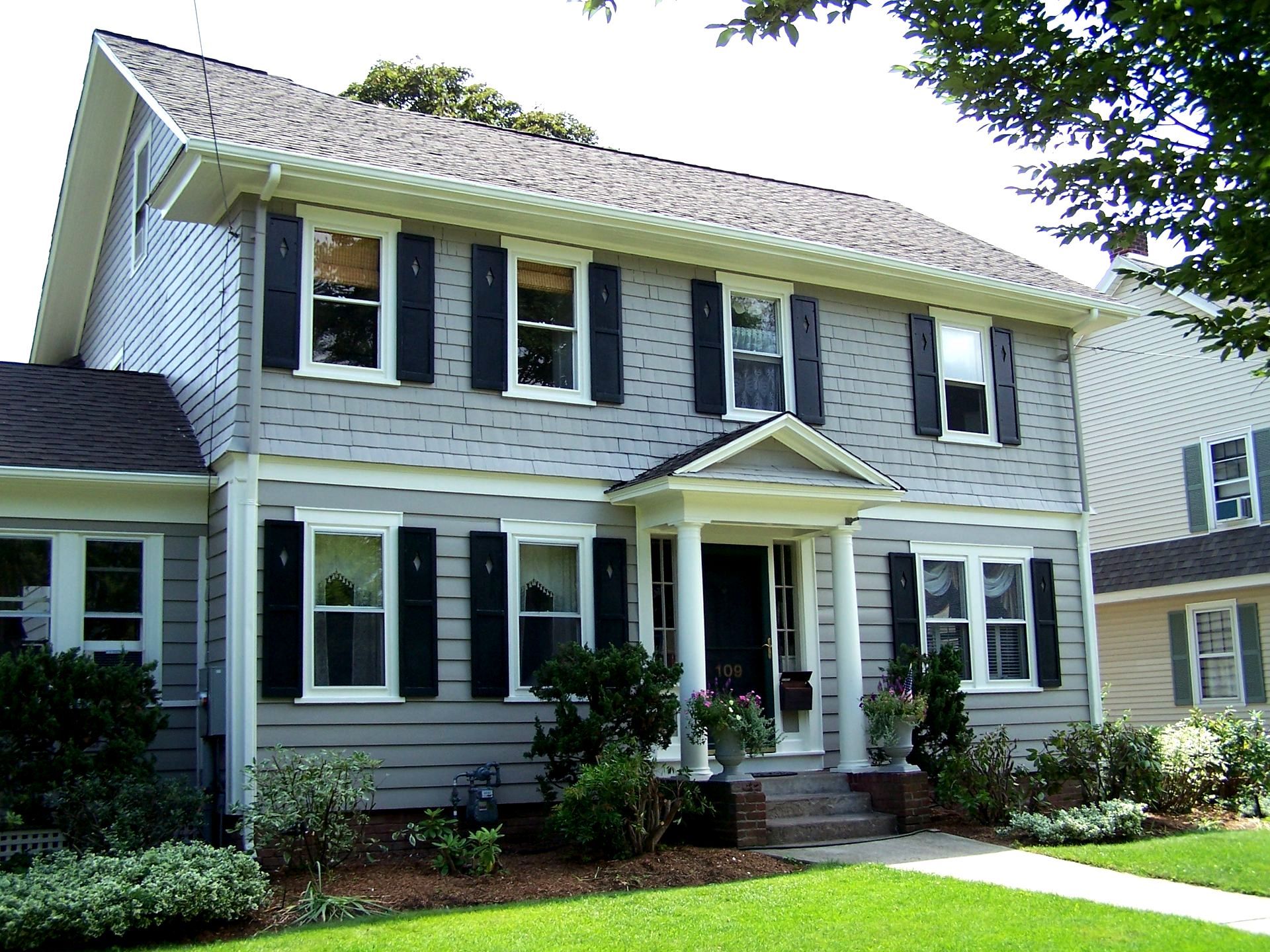 A gray house with black shutters on the windows
