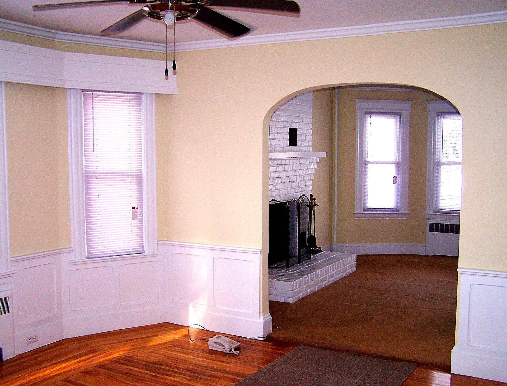 A living room with a fireplace and a ceiling fan