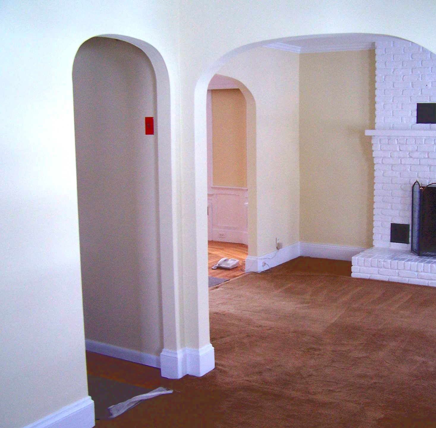 An empty living room with arches and a fireplace