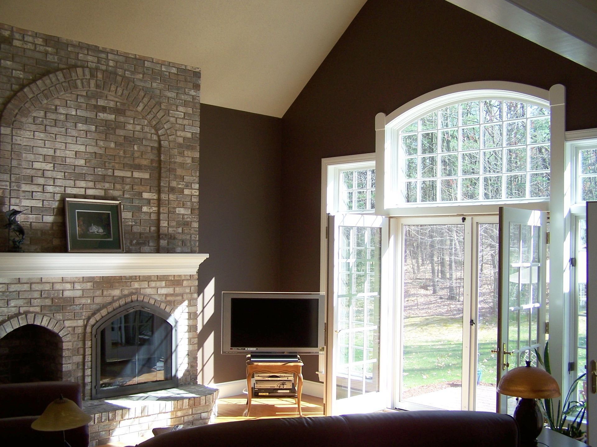 A living room with a brick fireplace and a flat screen tv