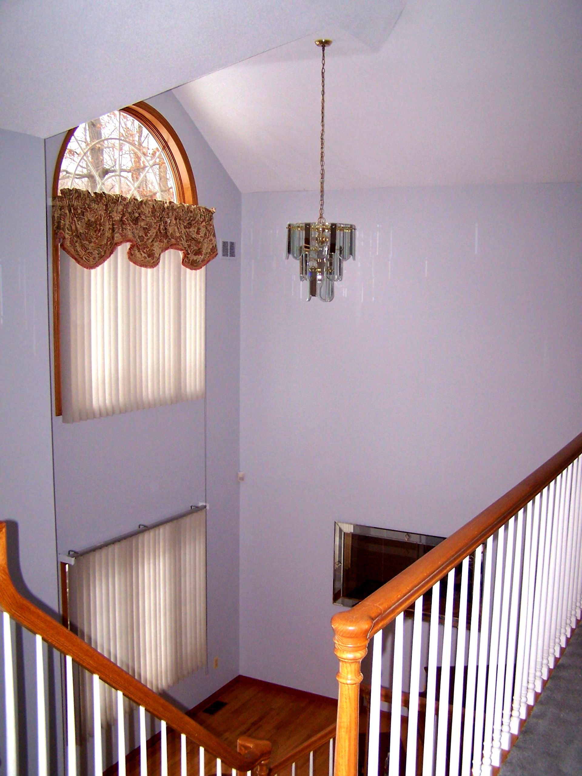 A staircase with a window and a chandelier hanging from the ceiling