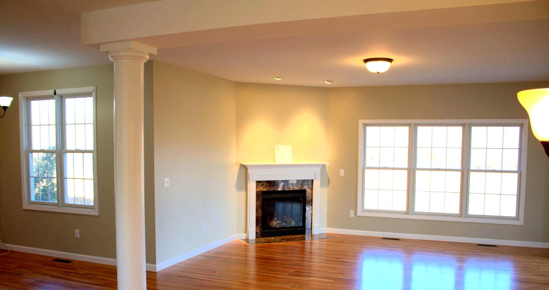 An empty living room with a fireplace and lots of windows