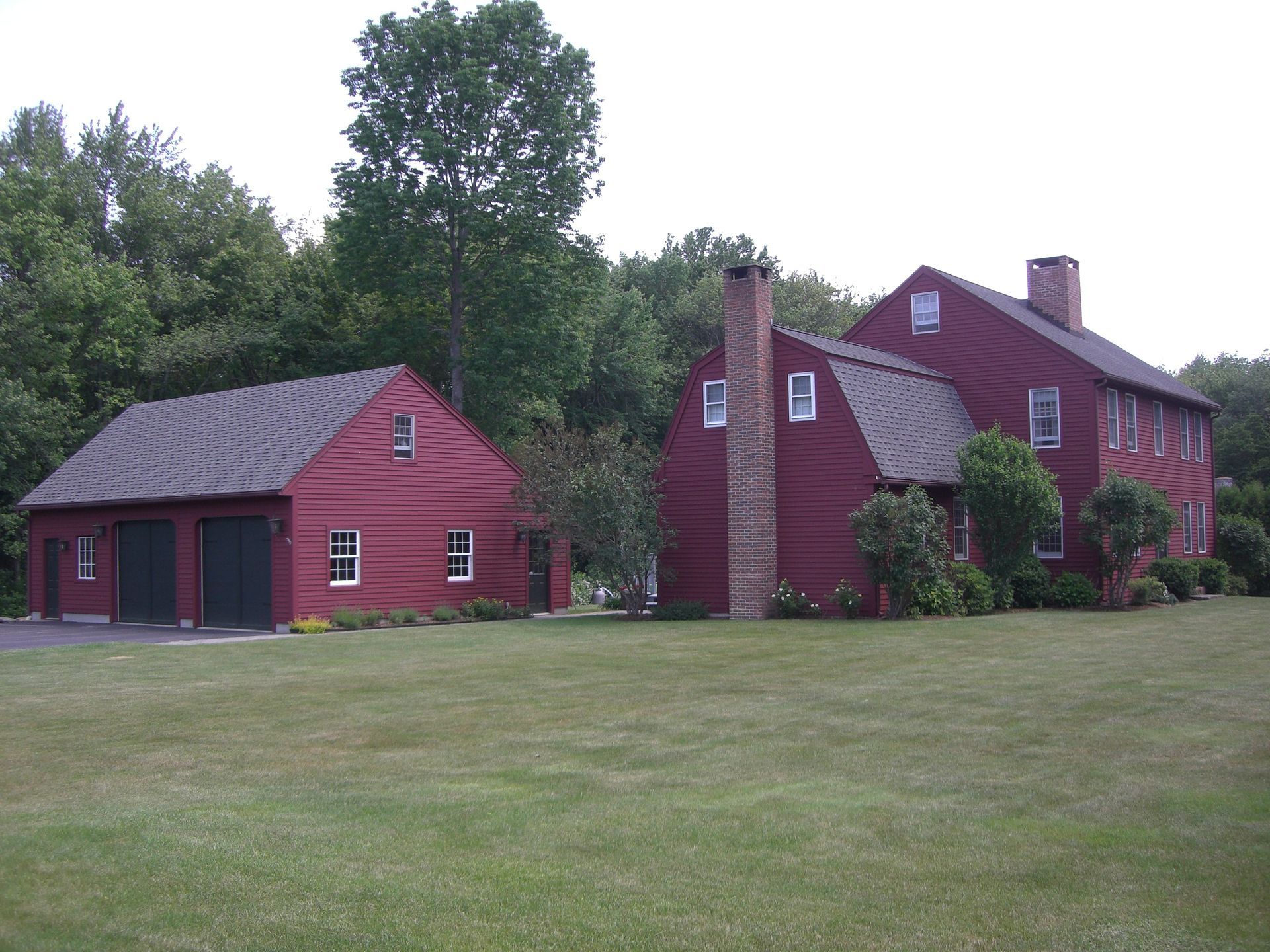 A large red house sits in the middle of a lush green field