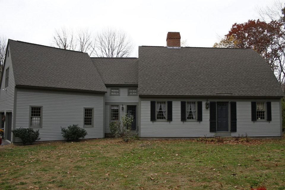 A large white house with a gray roof and black shutters