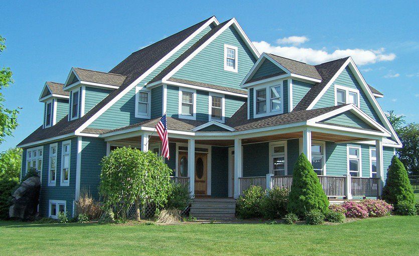 A large green house with a porch and an american flag