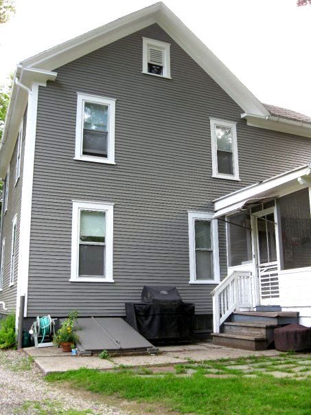 A gray house with white trim and a grill on the porch