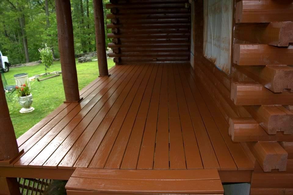 The porch of a log cabin has been painted brown