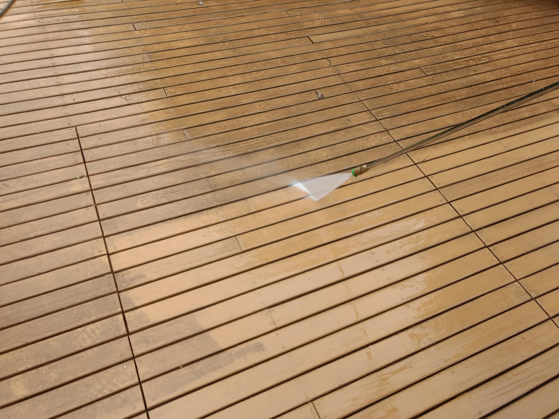 A person is cleaning a wooden floor with a high pressure washer