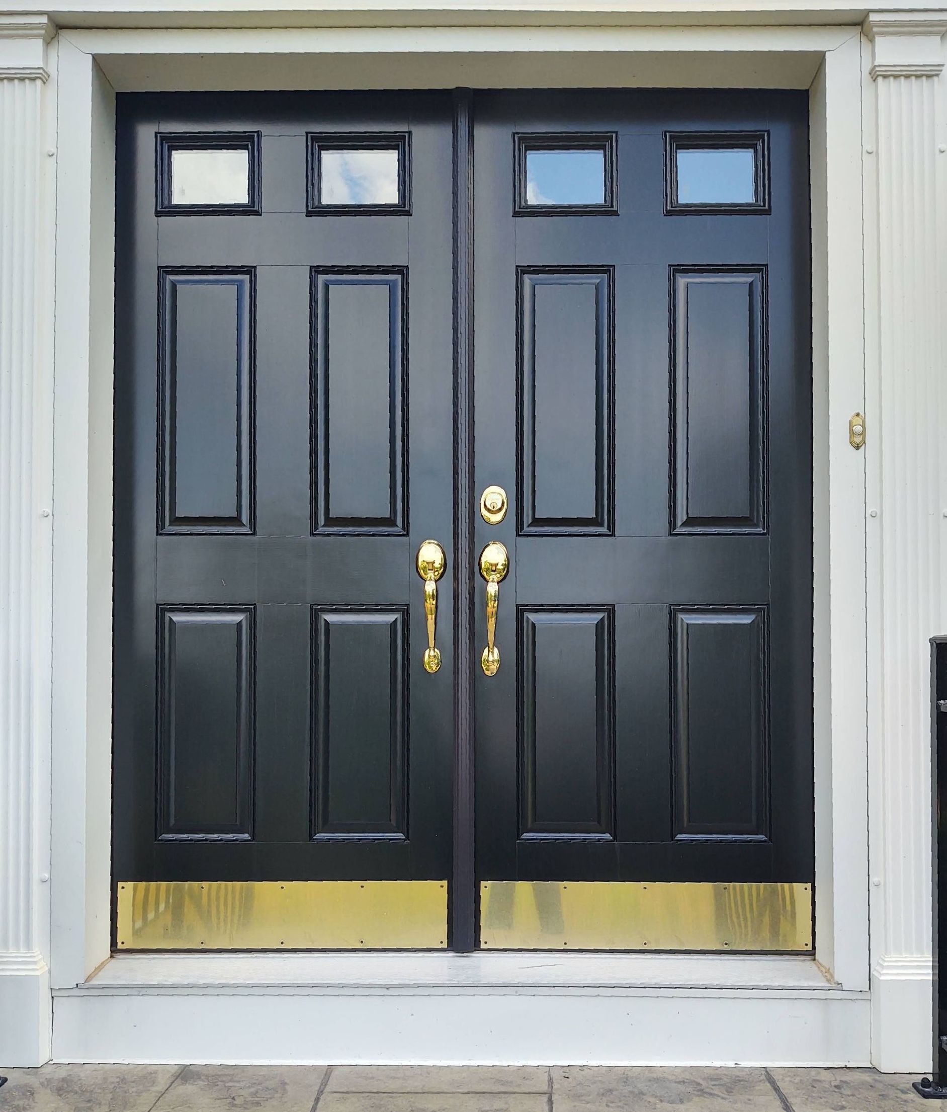 A pair of black doors with gold handles on a white building