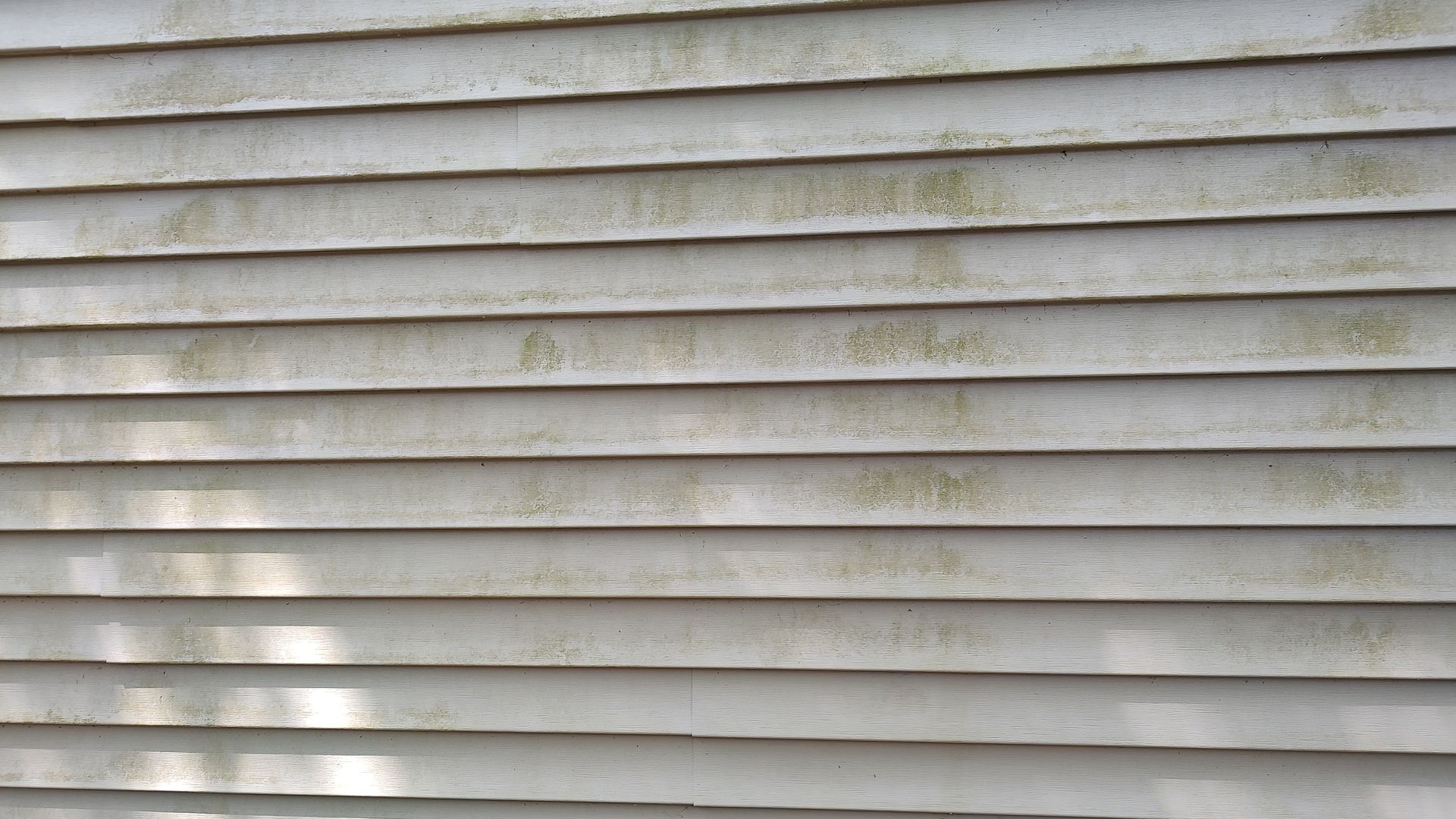 A close up of a white siding with a lot of stains on it.