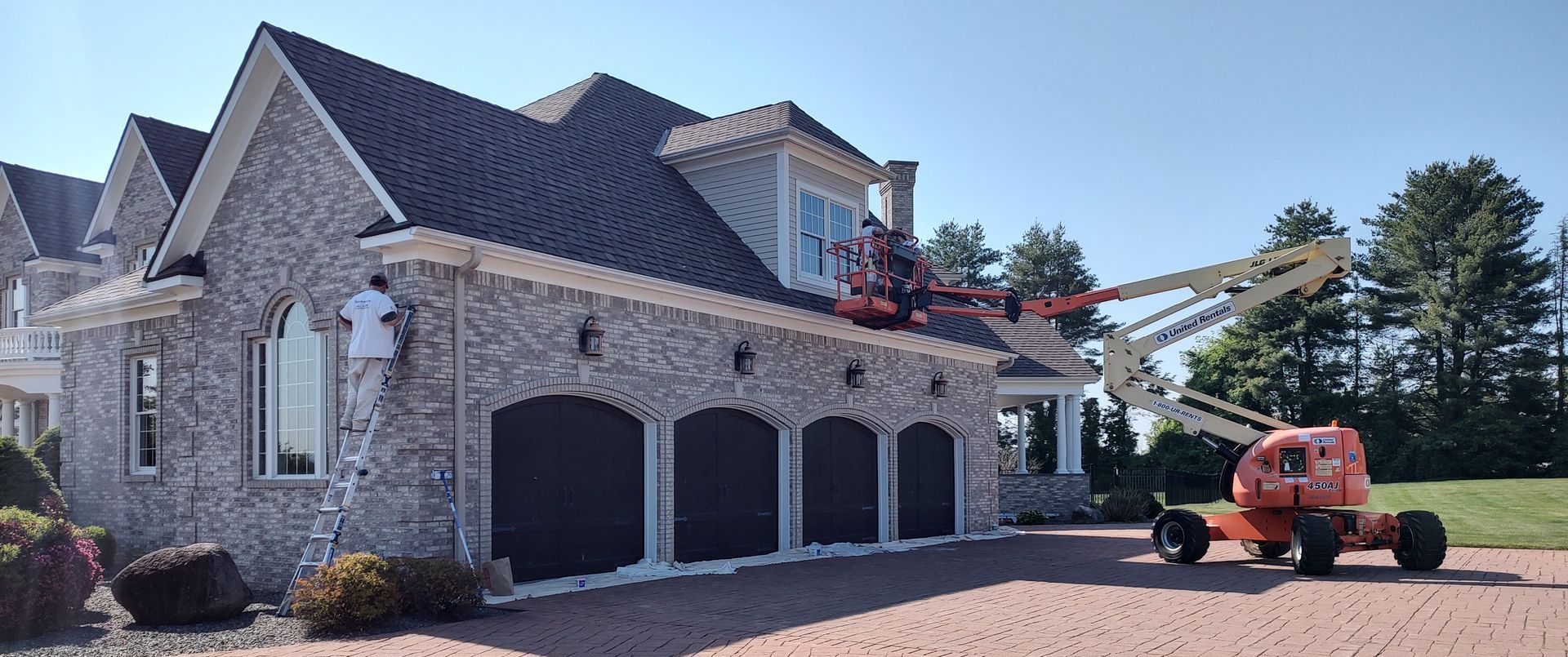 A man is painting the side of a large house.
