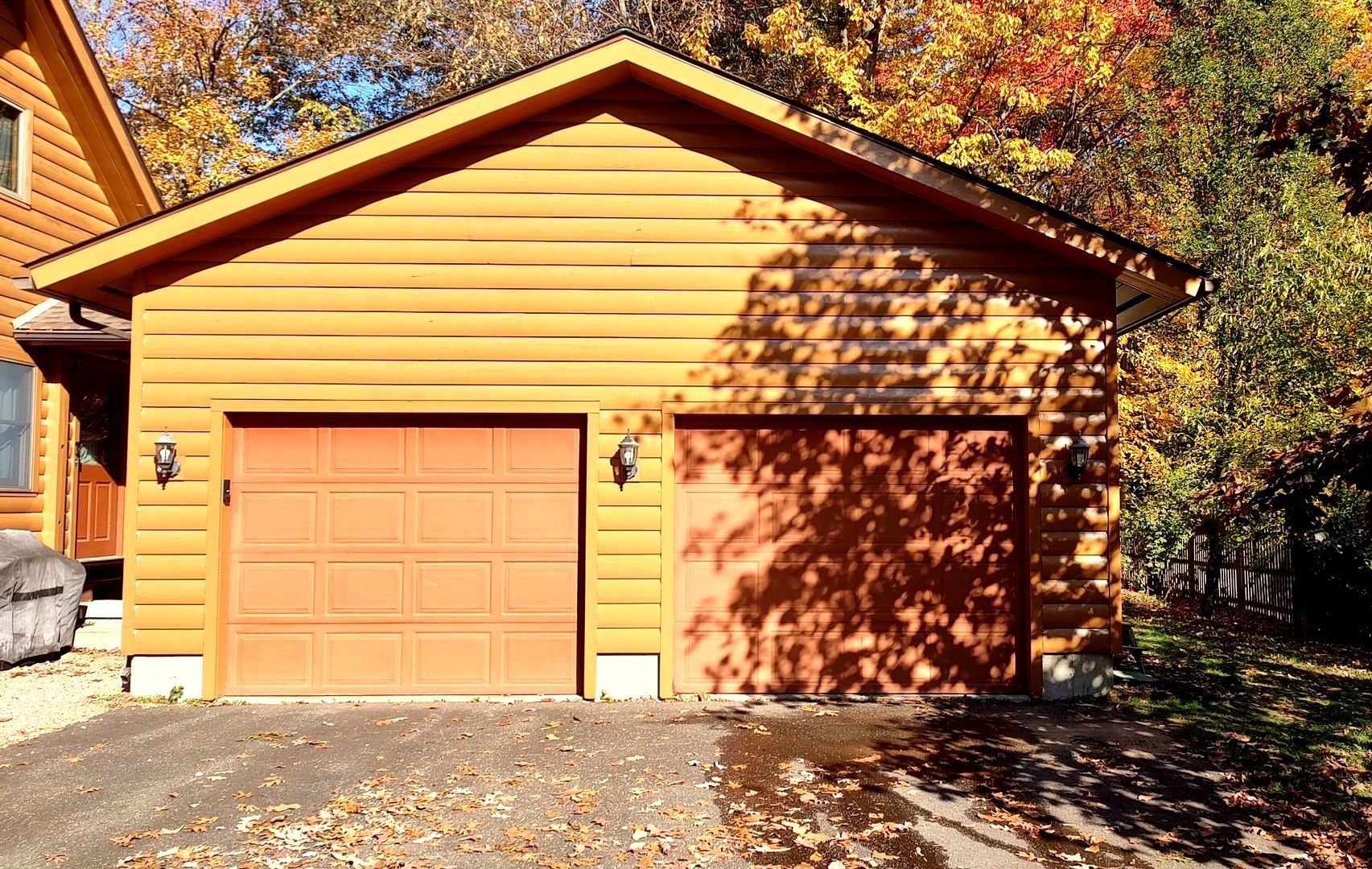 A garage with an orange garage door is next to a house.