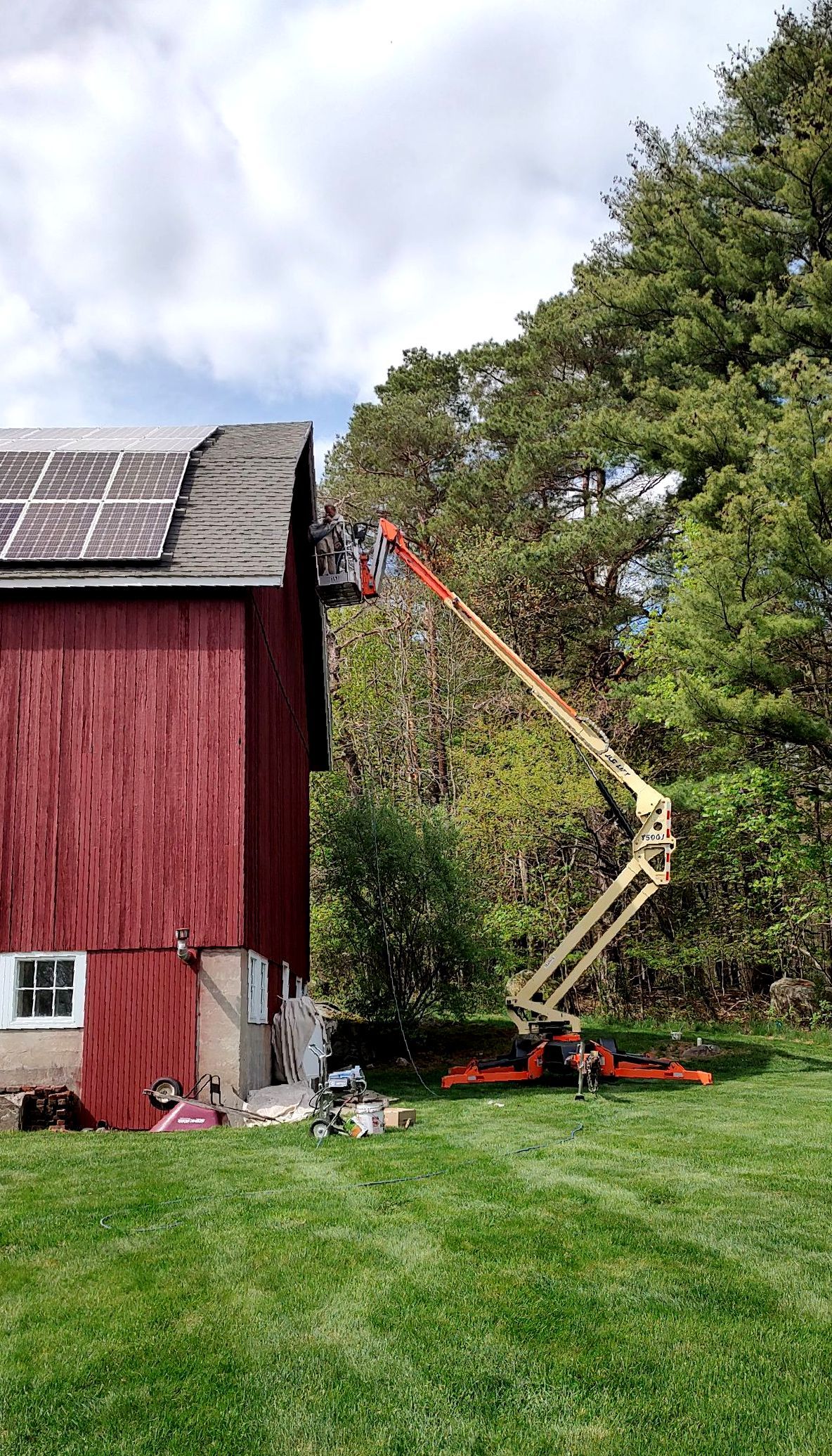 A man is installing solar panels on the roof of a barn.