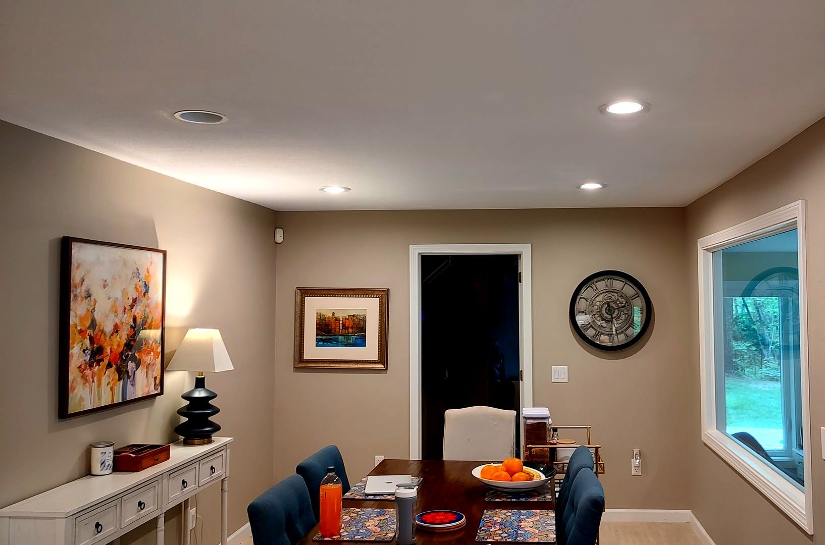 A dining room with a table and chairs and a clock on the wall