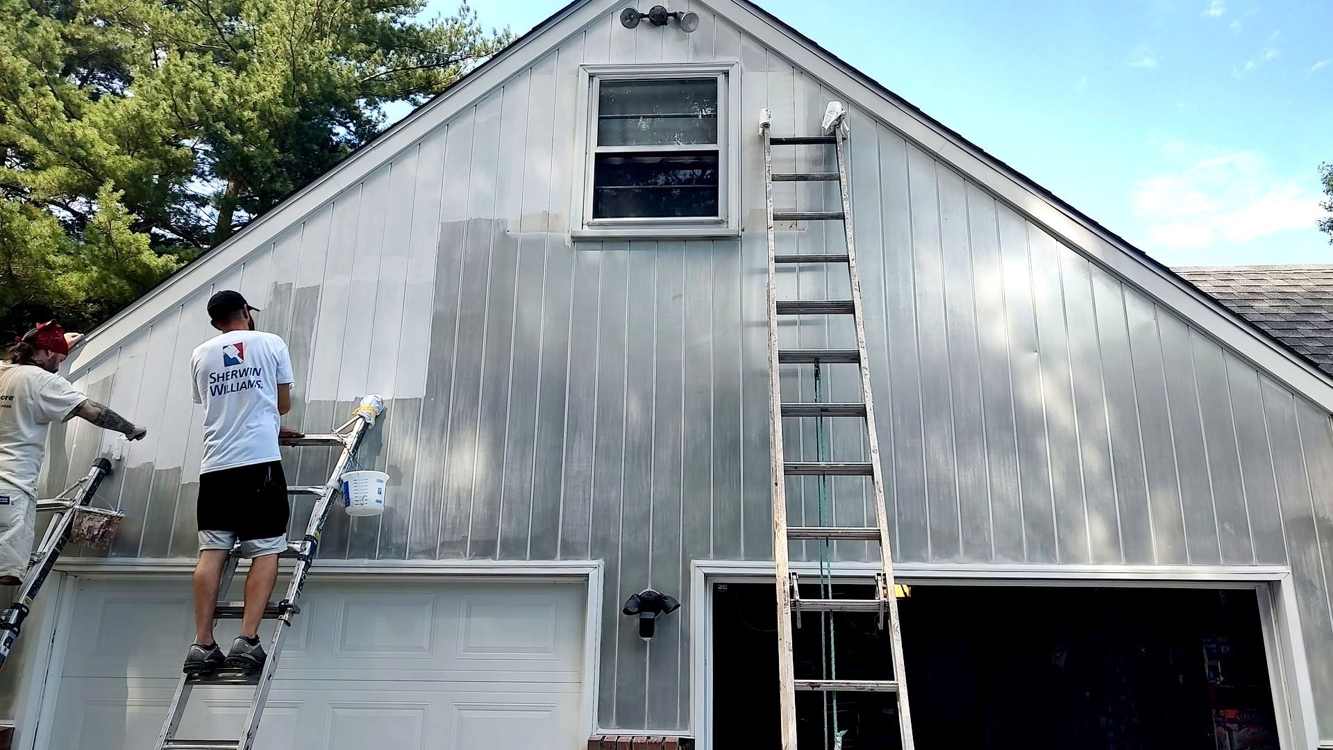 Two men are painting the side of a house.