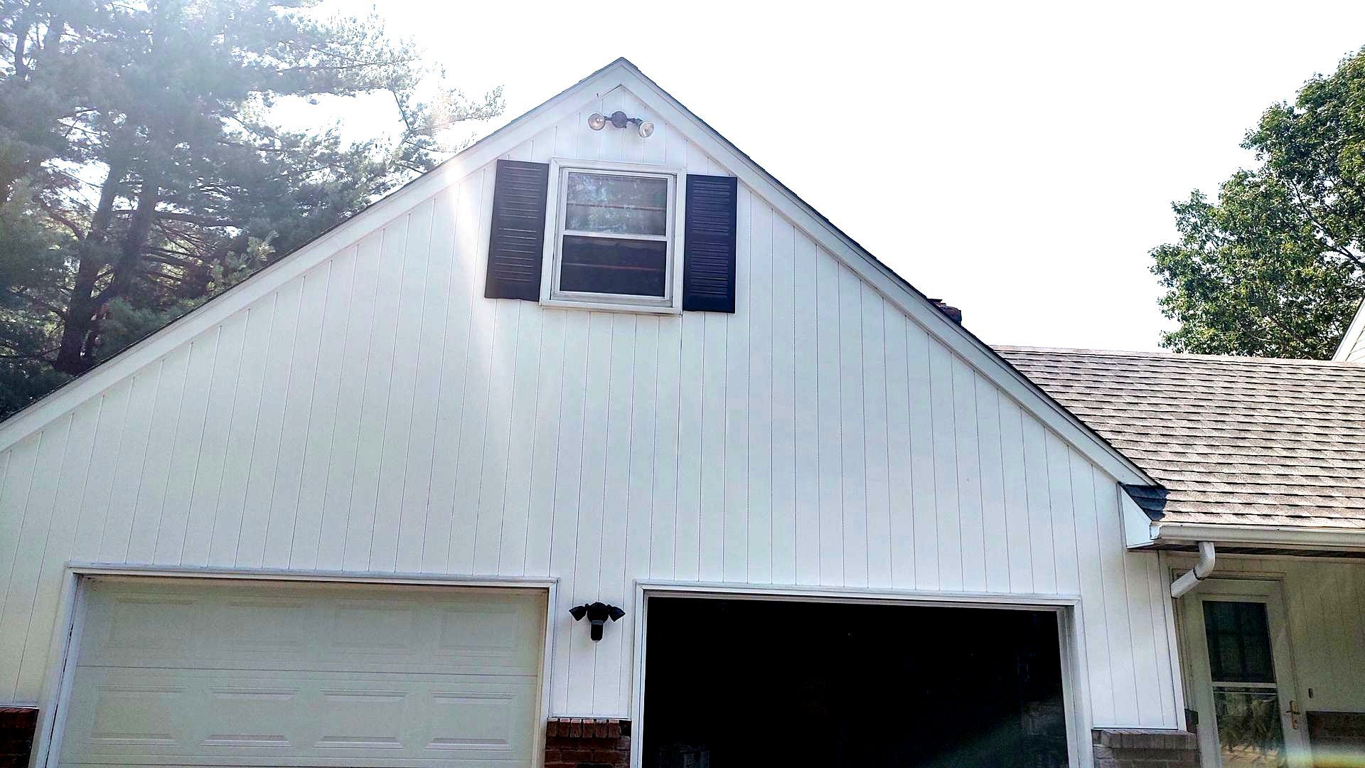 A white garage with black shutters on the windows