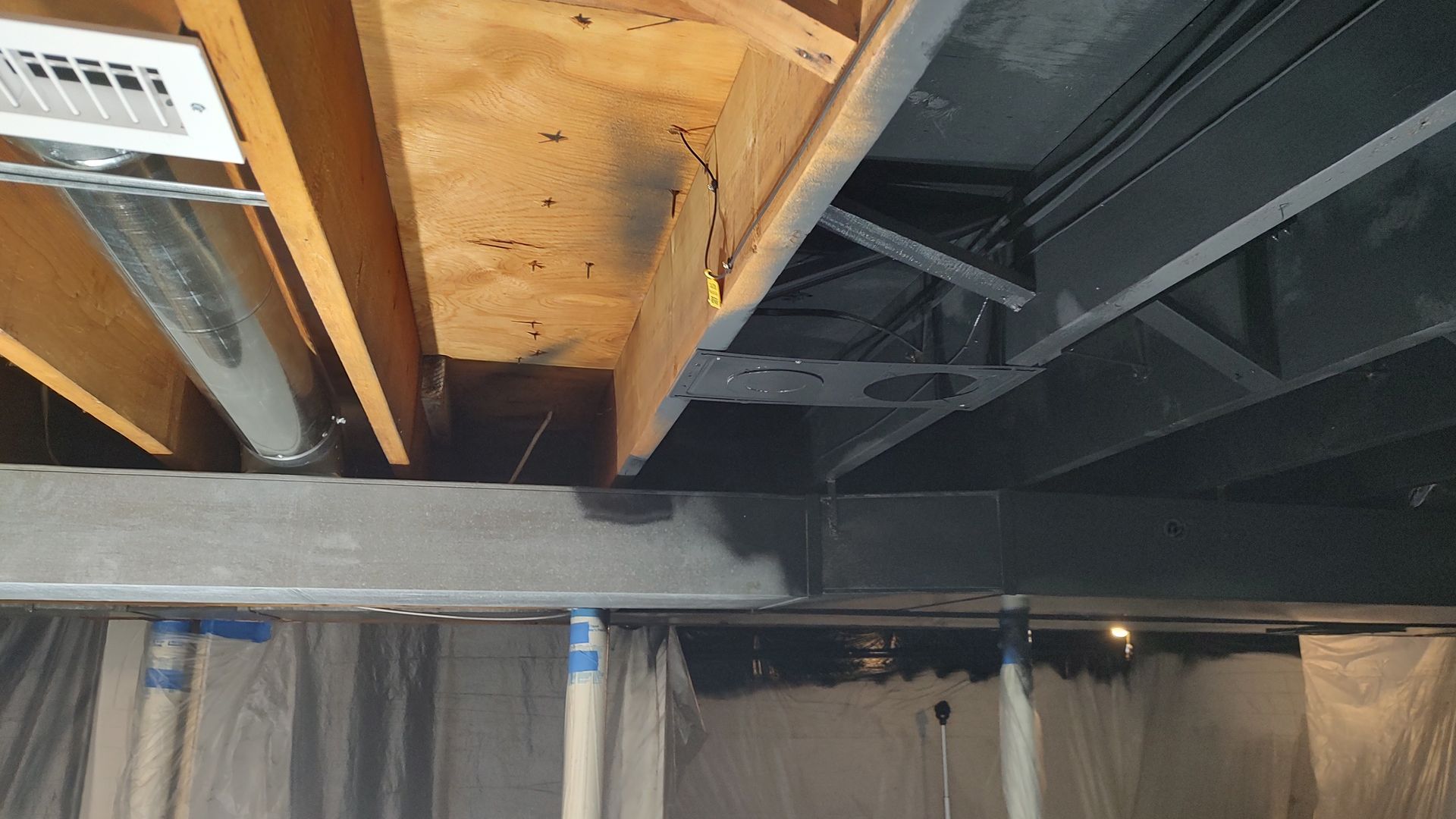 The ceiling of a basement is being painted black.