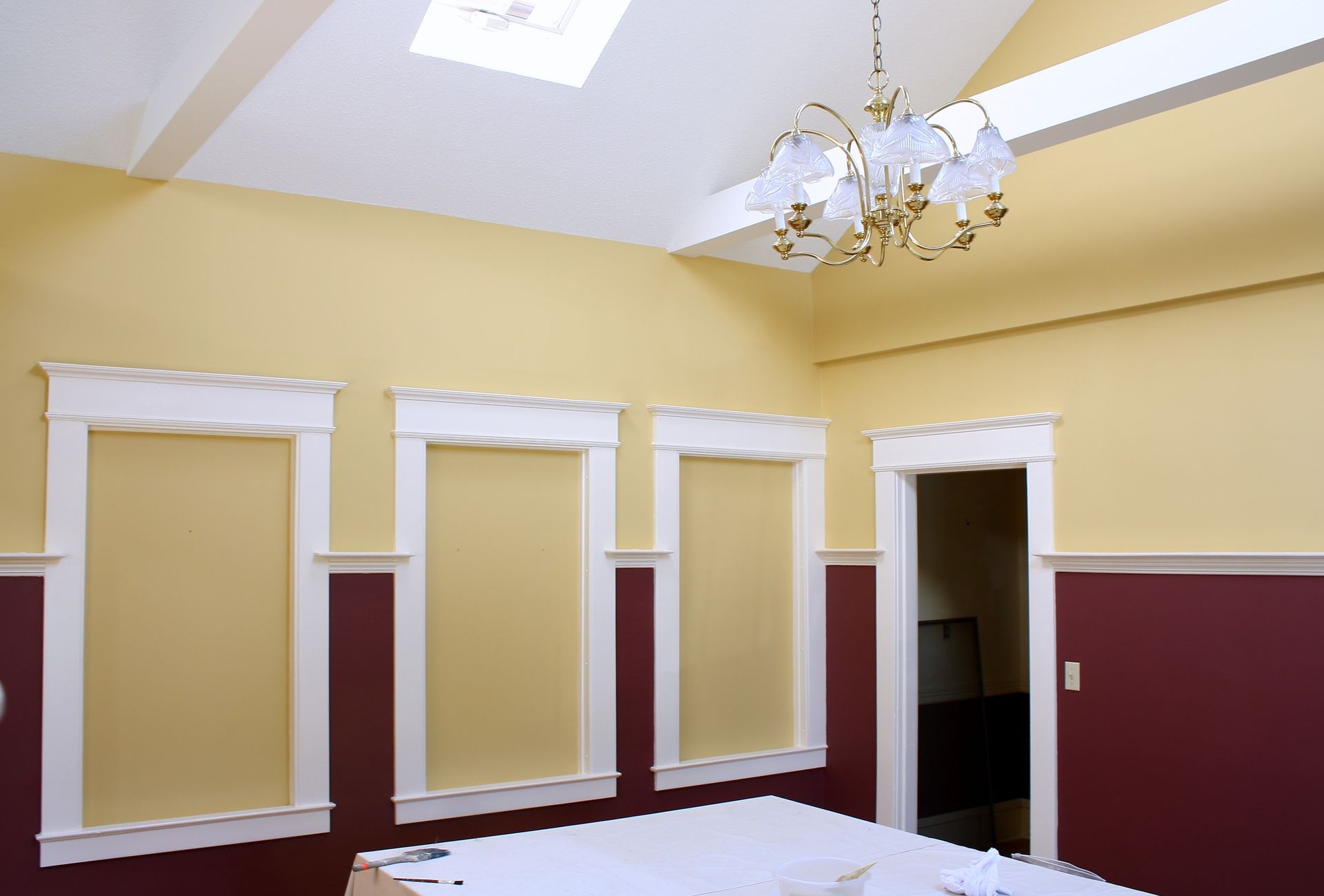 A room with yellow and red walls and a chandelier hanging from the ceiling