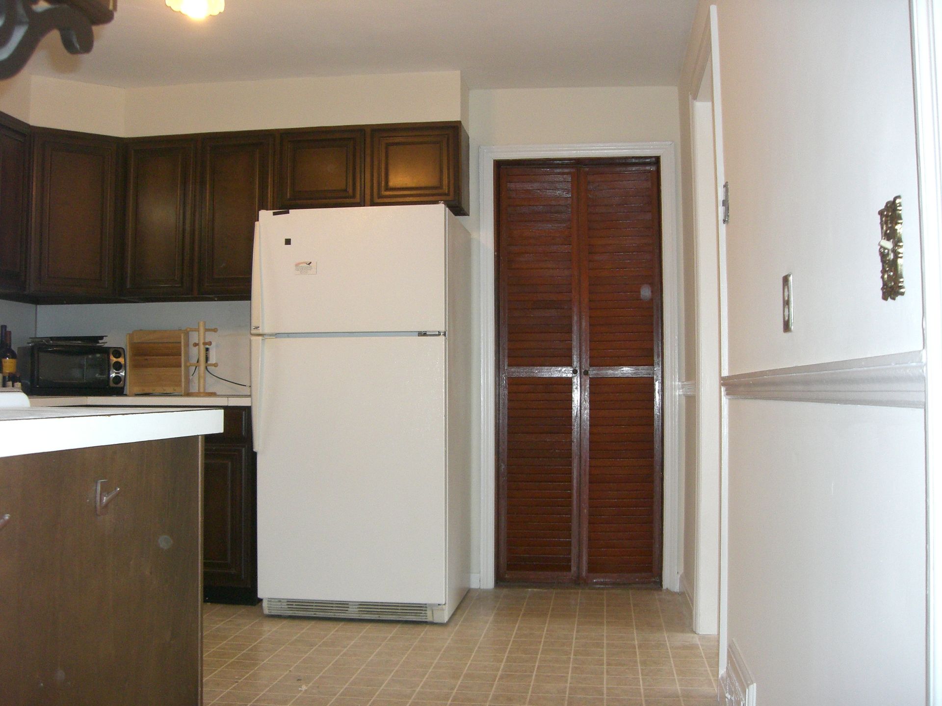 A kitchen with brown cabinets and a white refrigerator