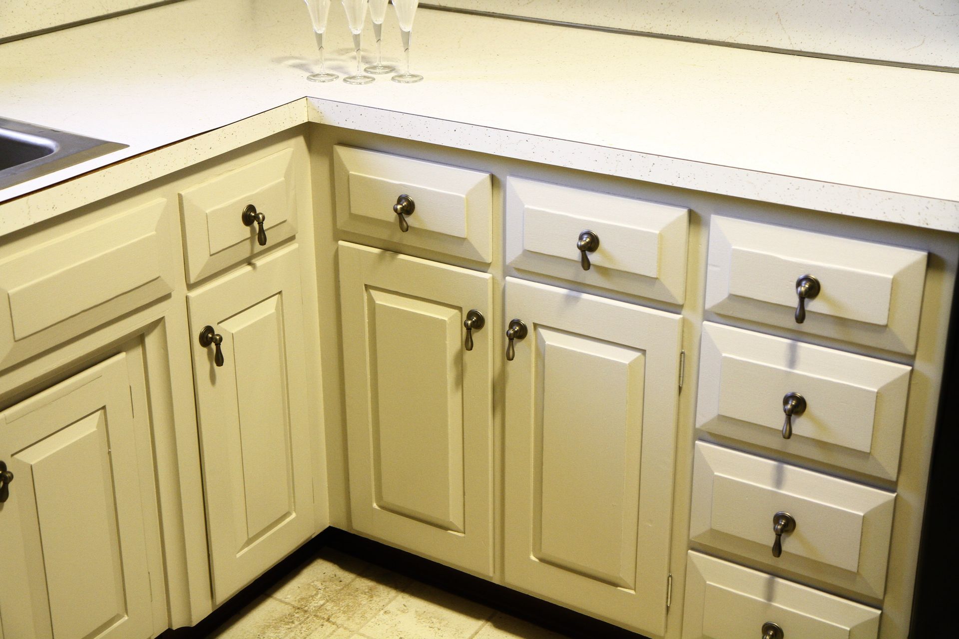 A kitchen with white cabinets and drawers and a sink