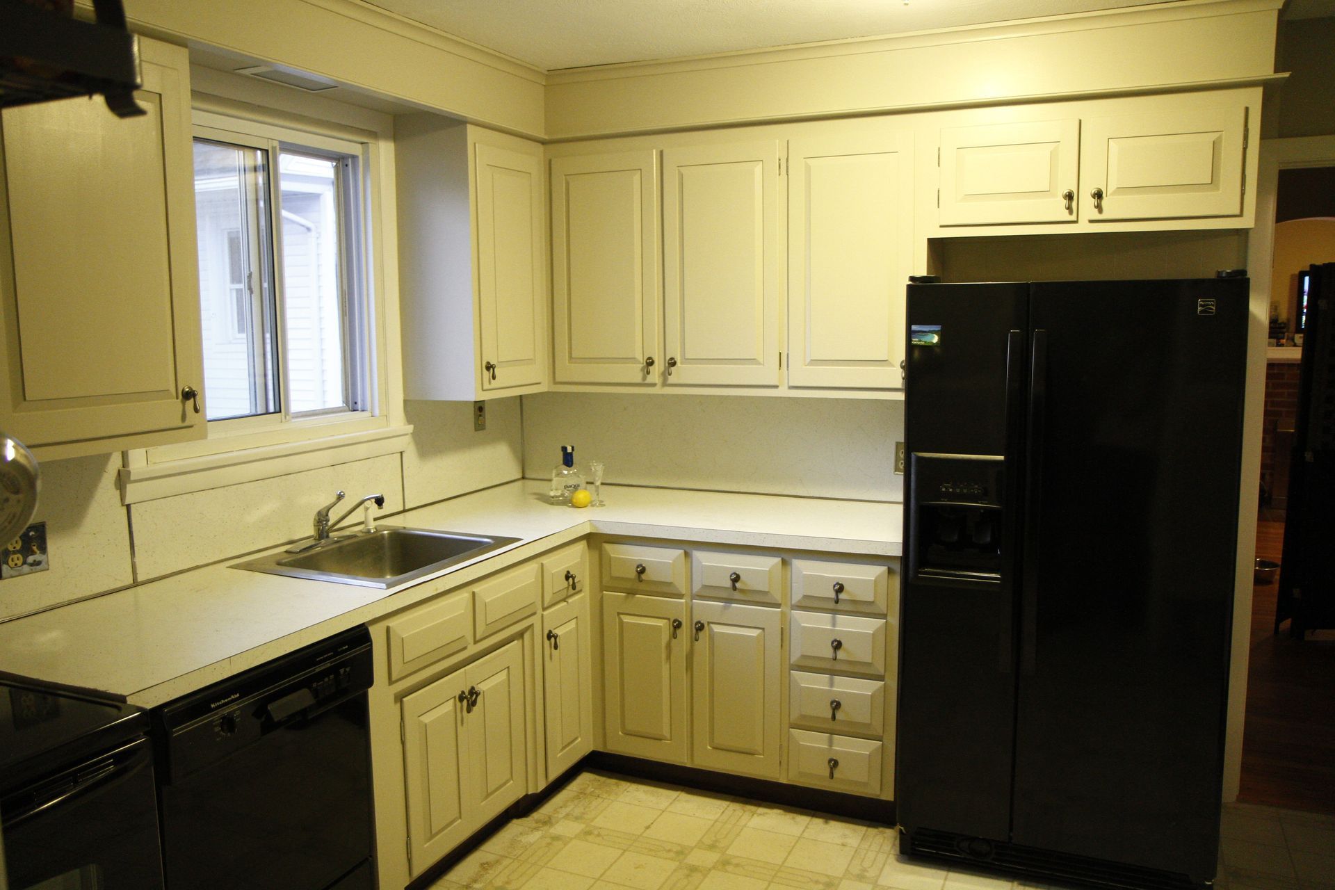 A kitchen with white cabinets and a black refrigerator