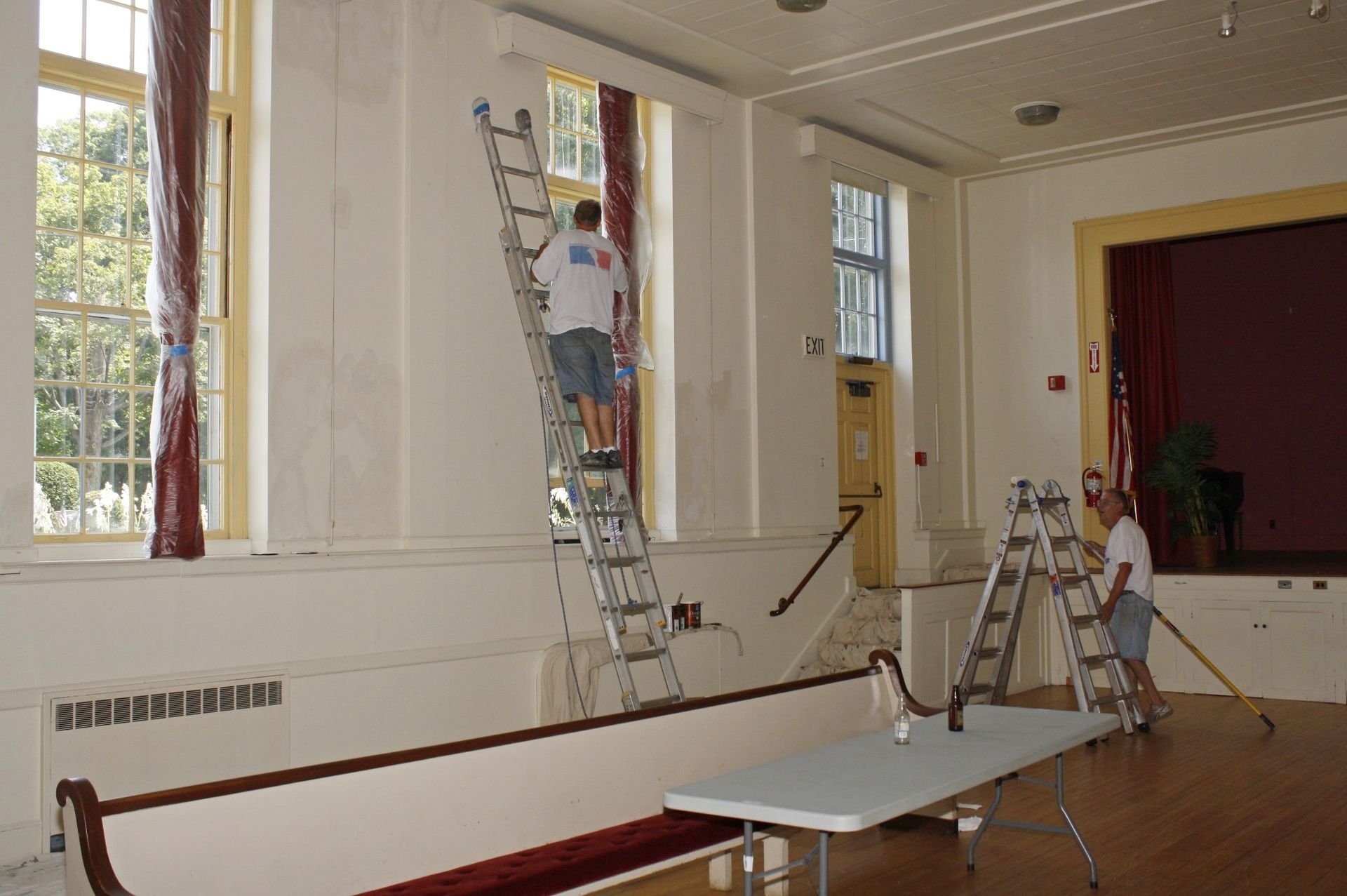 A man on a ladder painting a wall in a room