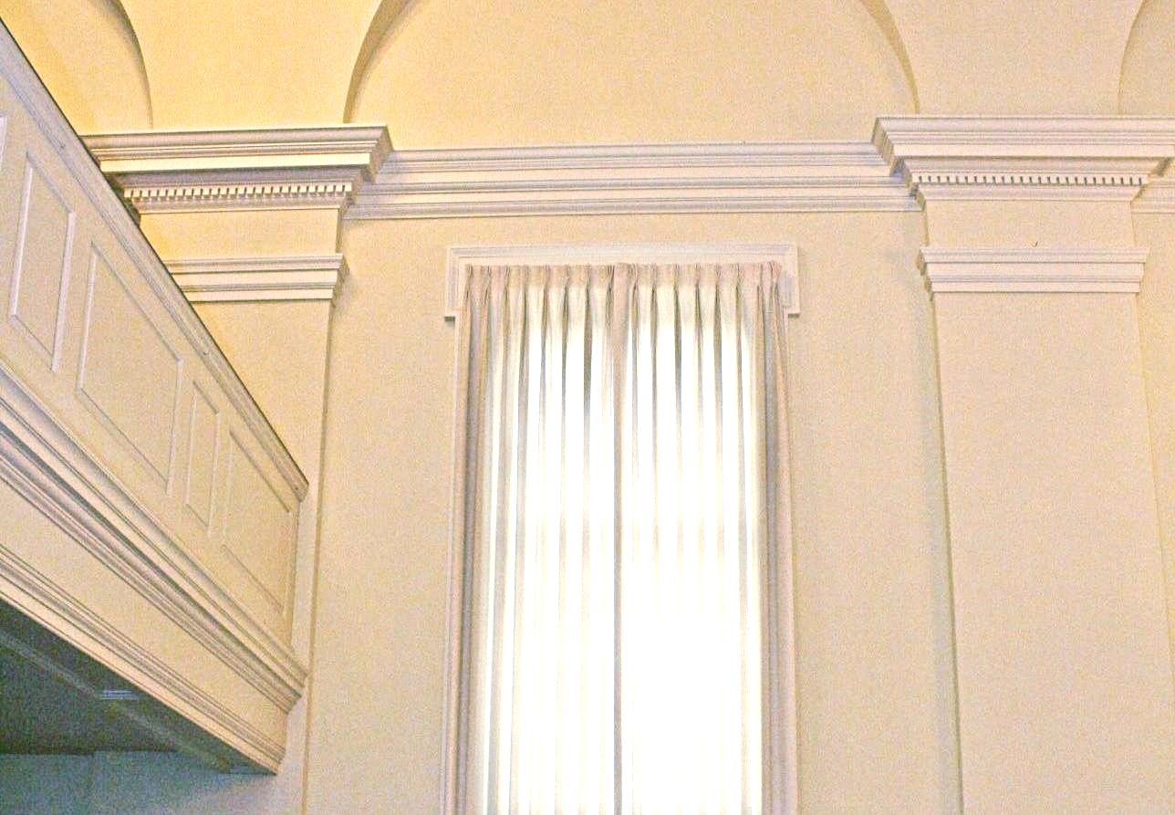 A room with arched ceilings and a window with white curtains