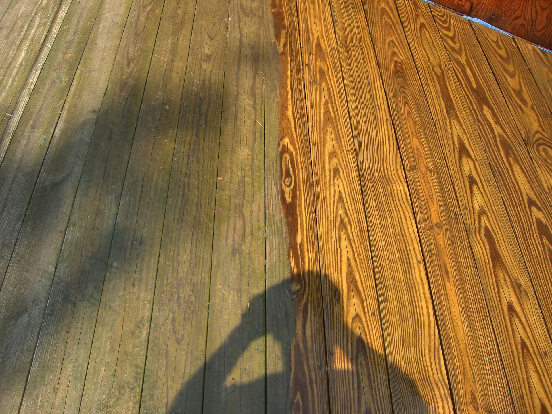 A shadow of a person is cast on a wooden deck