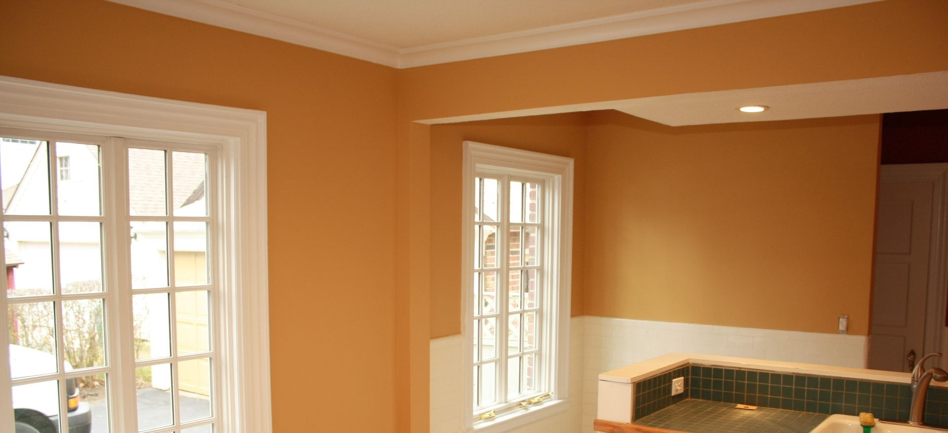 A kitchen with orange walls and white trim and a large window
