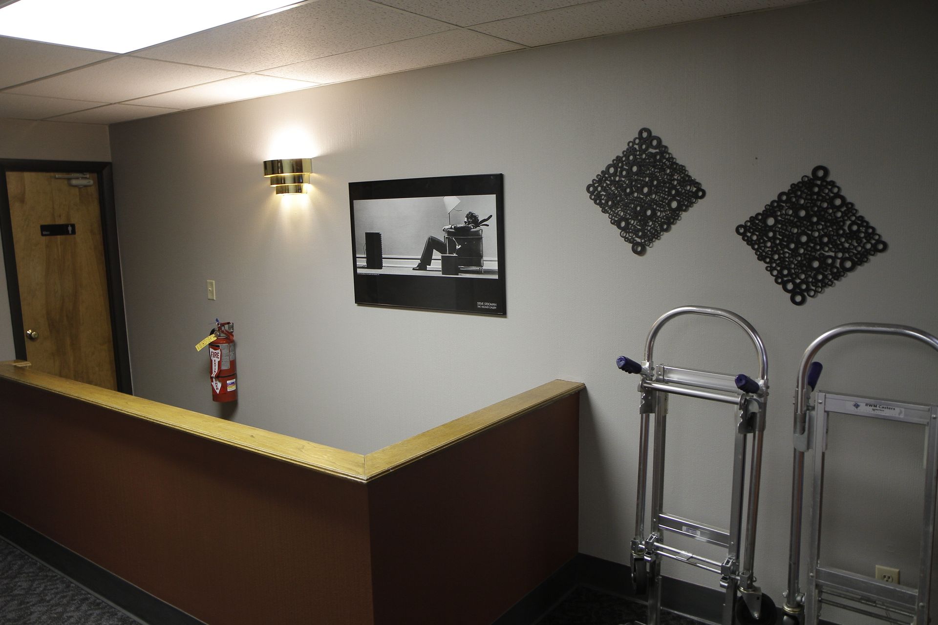 A hallway with a picture on the wall and a fire extinguisher