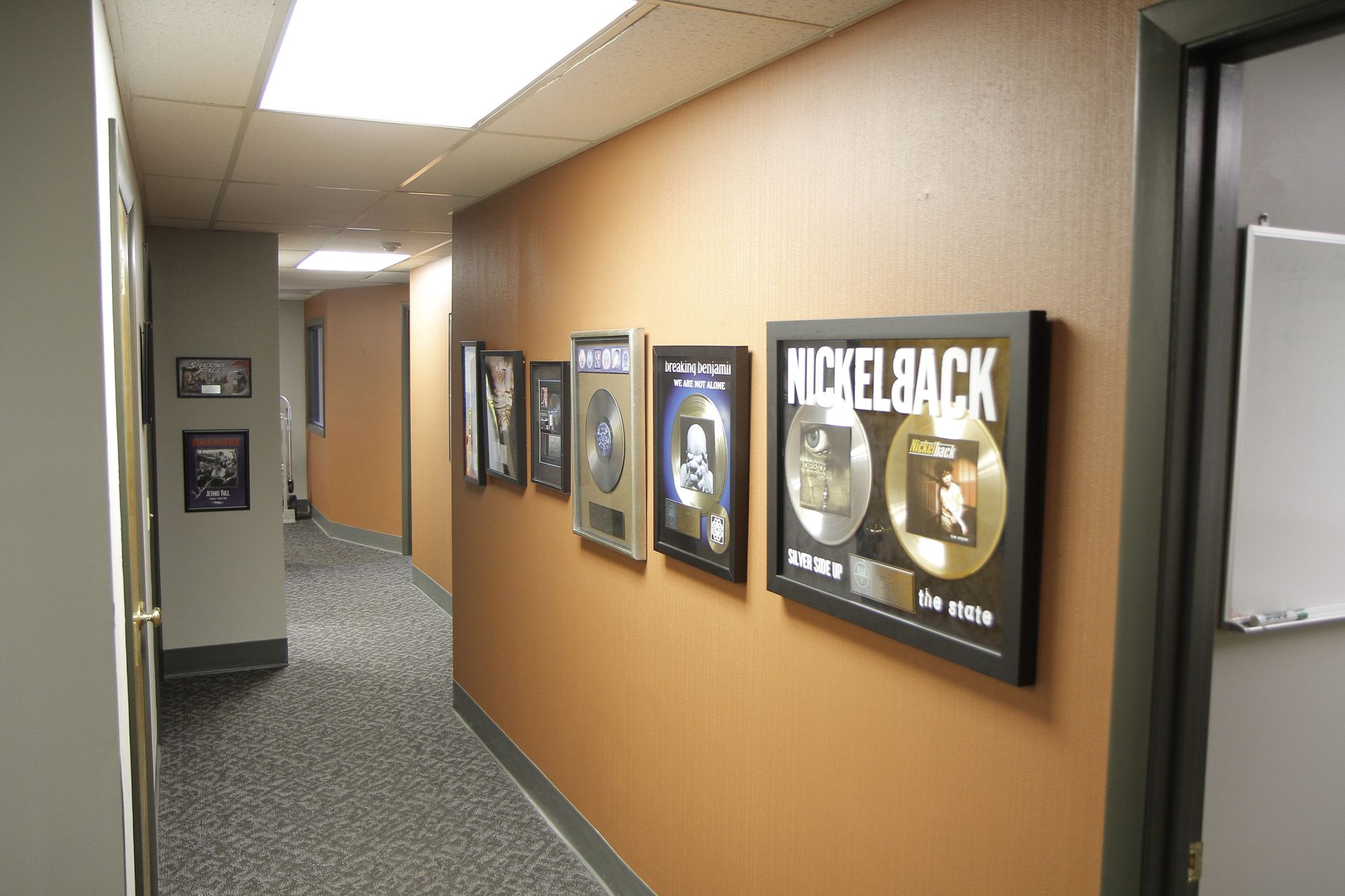A hallway with framed pictures of nickelback on the wall