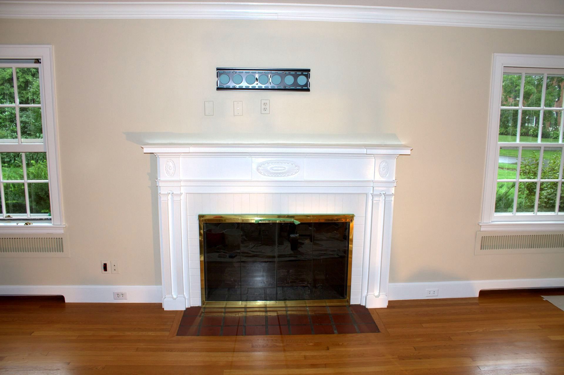 An empty living room with a fireplace and two windows