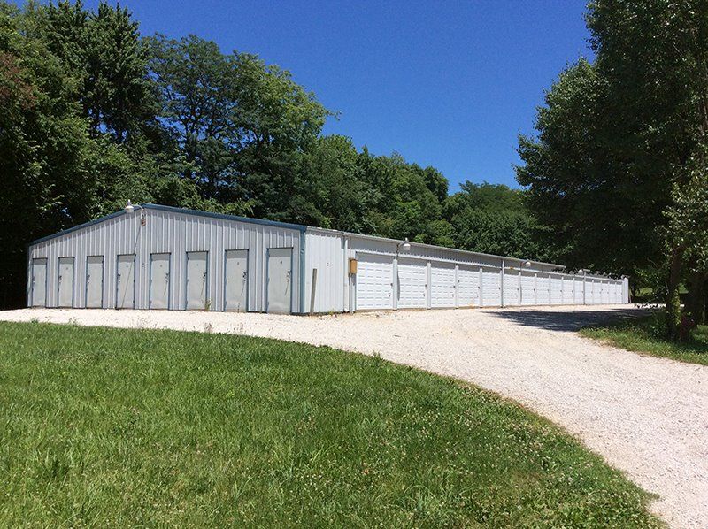 A row of storage units are lined up in a grassy field.