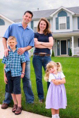 Debt Relief — Family Smiling Beside  A House in Chicago, IL