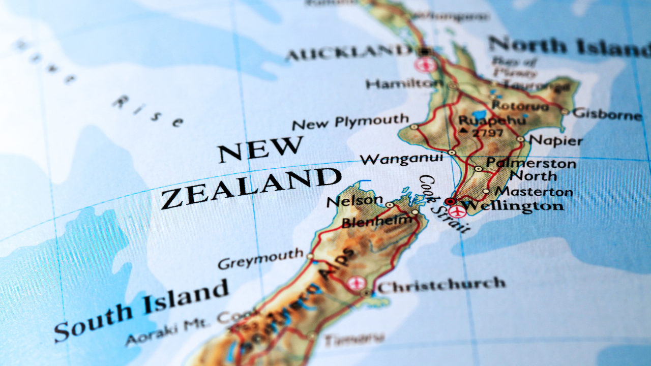 Map of New Zealand with North and South Islands labeled, highlighting major cities like Auckland and Wellington.