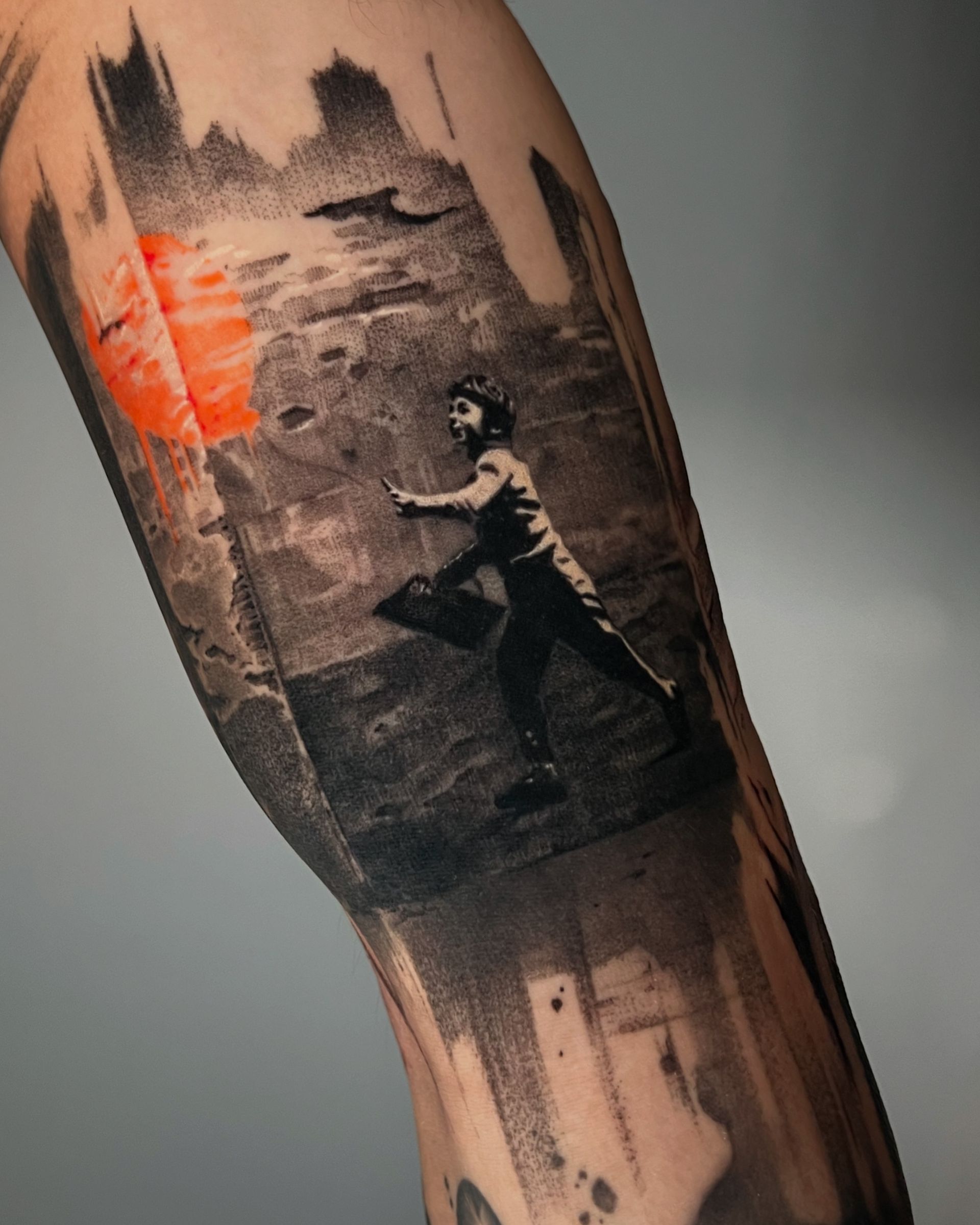 A tattoo on an arm depicting a person running against a dark, textured background with a bright orange circular shape.