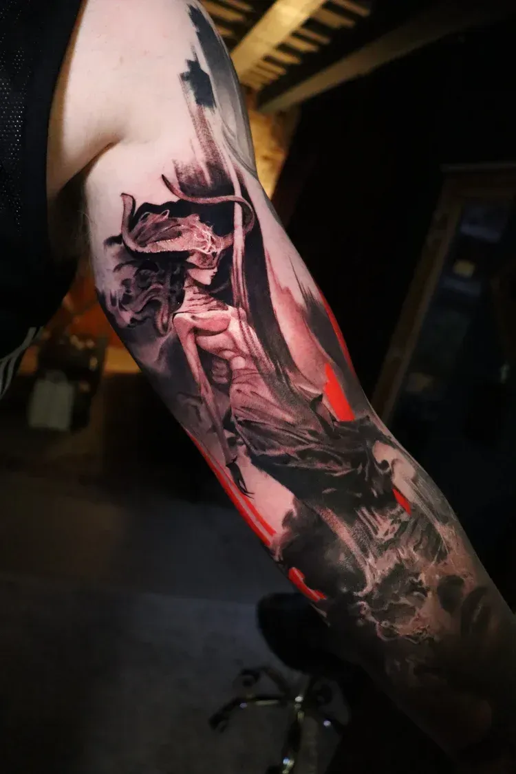 A forearm tattoo in a dark, illustrative style featuring a horned, ethereal figure with red accents on a shadowy background.