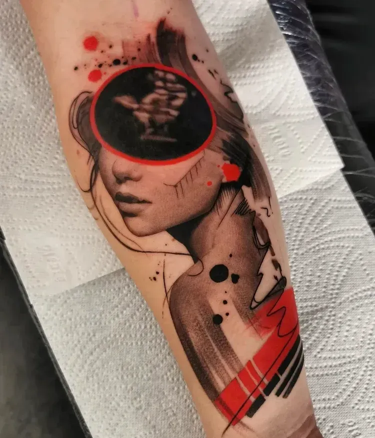 A forearm tattoo featuring a stylized portrait with a red circle obscuring the eyes, containing an intricate hand gesture.