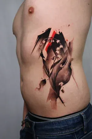 A side-view of a tattoo featuring black ink lily of the valley flowers with abstract brushstrokes and red accents.