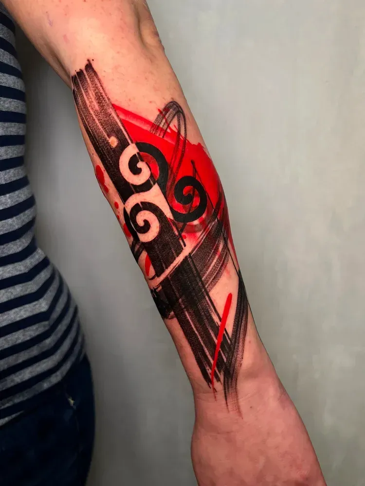 A forearm tattoo featuring bold black brushstrokes and vibrant red splashes, with stylized spiral patterns integrated.