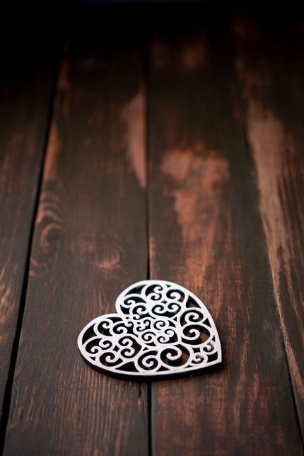 Adorno de corazón de filigrana de plata sobre tablones de madera oscura.